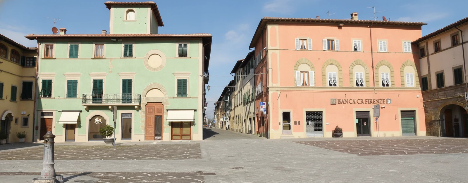 Piazza Vittorio Emanuele a Castelfranco di Sopra con il palazzo verde chiaro con la torretta, il palazzo rosa e la pavimentazione in pietra decorata